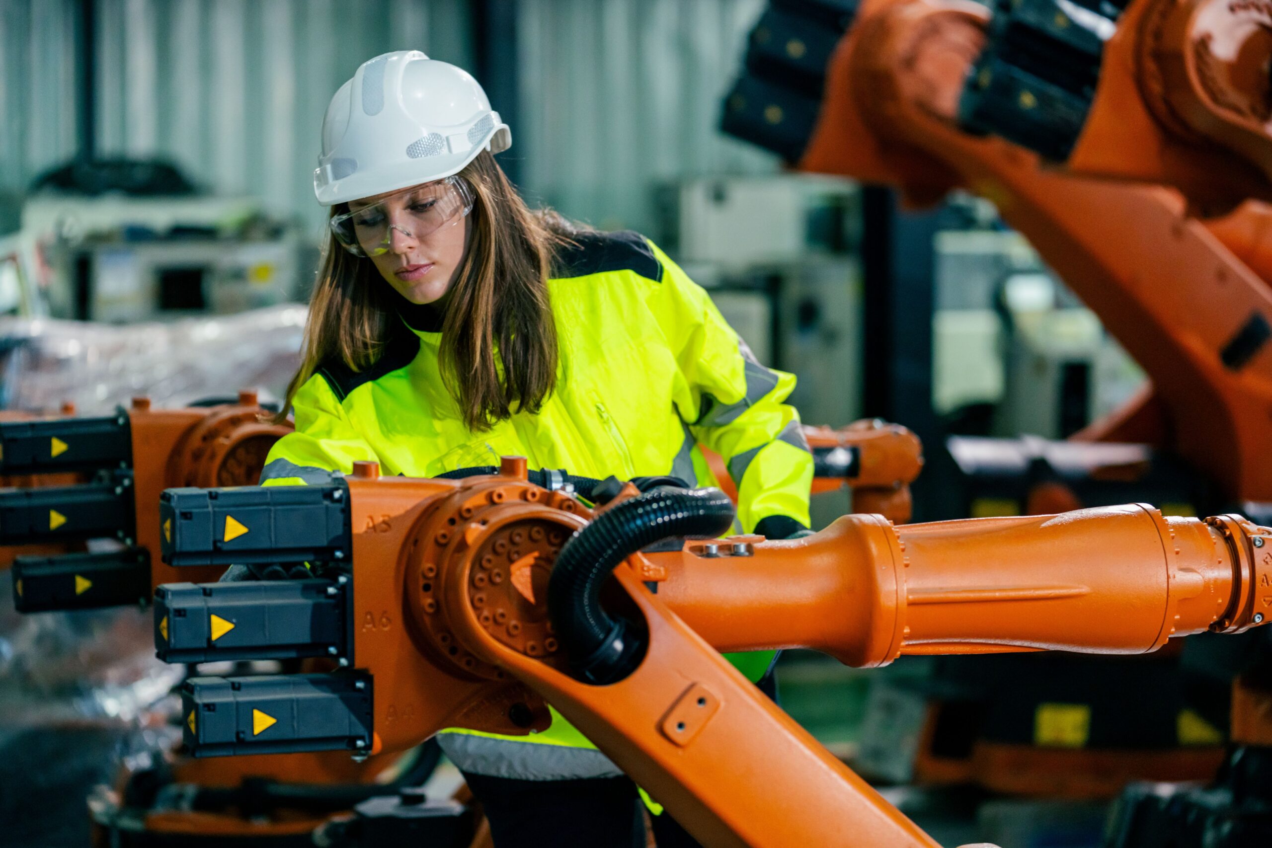 Ingenieurin überprüft den Kabelbaum in einer automatisierten Produktionsanlage mit Industrierobotern